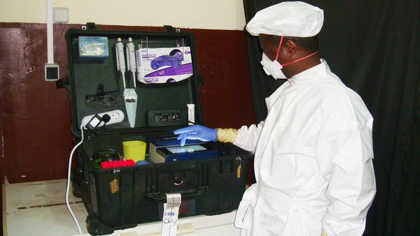 A technical assistant performing the Ebola-RPA test in the mobile diagnostics suitcase in Guinea.